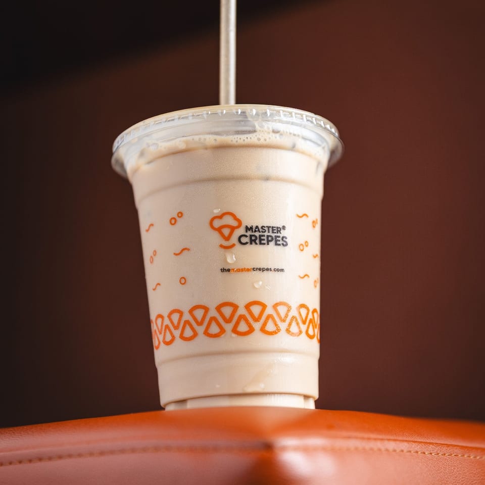 Chilled drink in a Master Crepes cup on an orange seat